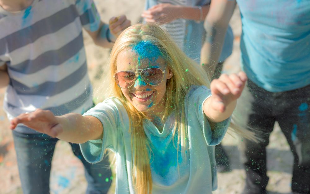 Woman Throwing Colorful Powder in the Crowd Amidst Hindu Holi Festival Celebrations.