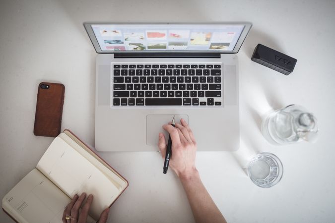 A person is working on a macbook laptop and on a table