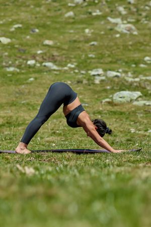 Woman in a grass field doing downward dog yoga pose