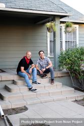 Portrait of cheerful married couple sitting on steps in front of a house smiling 48Brj0