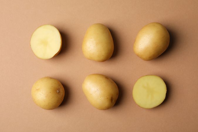 Two rows of potatoes on light brown background