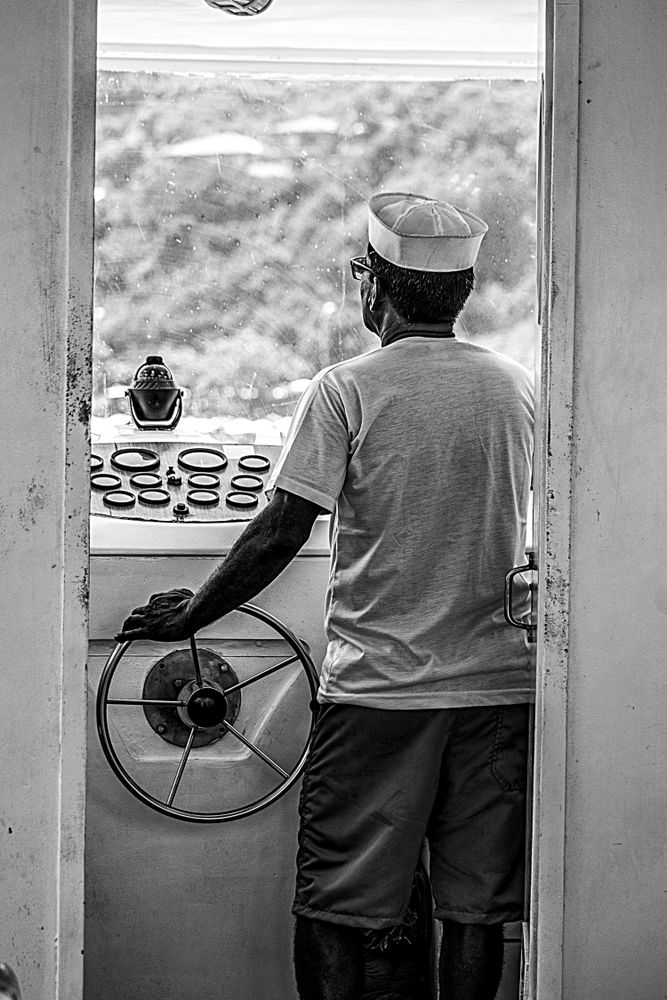 Back view of an older man driving a yacht