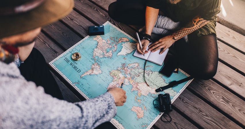 Top view of man and woman planning tour using a world map