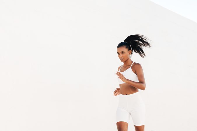 Slim woman in fitness gear others running outdoors