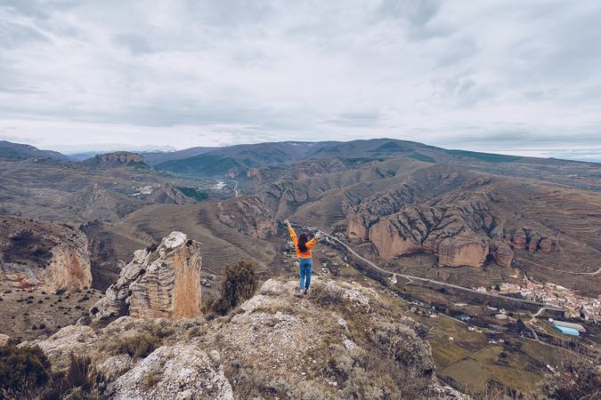 Carefree tourist woman cheering while standing at hill top
