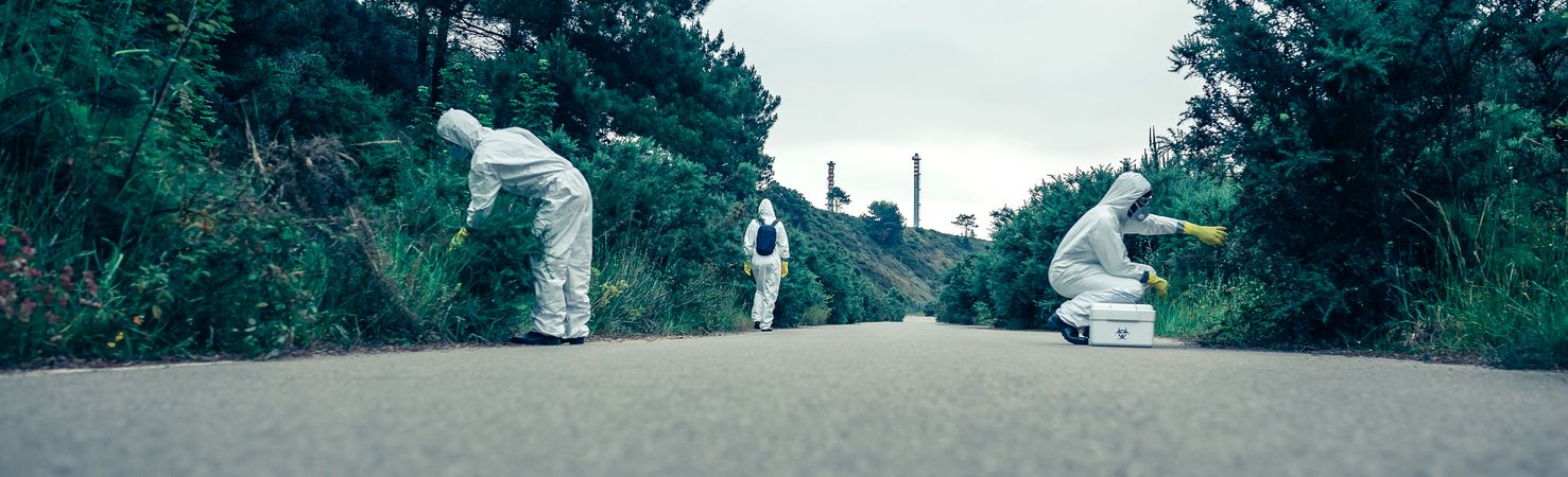 People in bacteriological protection suits looking for samples on empty road