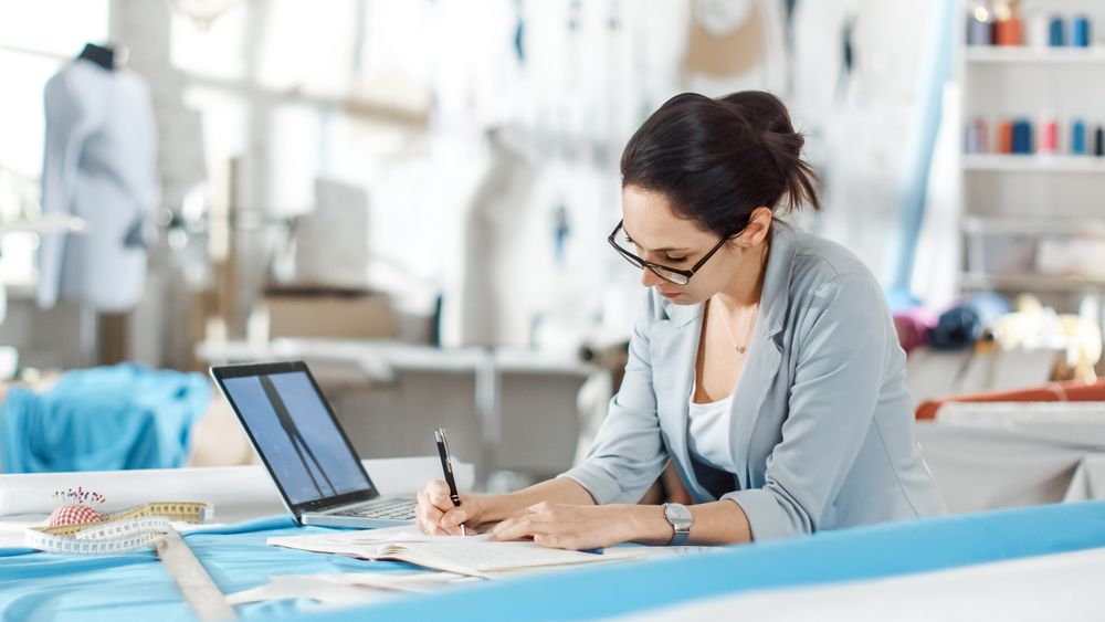 fashion, designer,  Sits at Her Desk, Uses Smartphone.