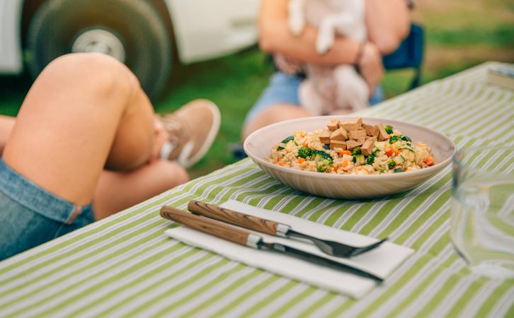 Close up of vegetable dish on outdoor table with people sitting in background