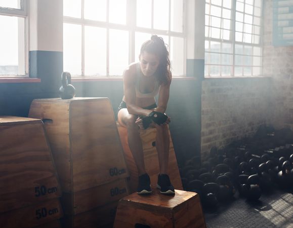 Fitness woman sitting on a box at gym after her workout