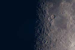View of moon’s craters illuminated along lunar terminator line.
