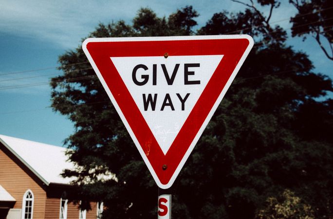 Red Give Way Traffic Sign Against A Clear Blue Sky
