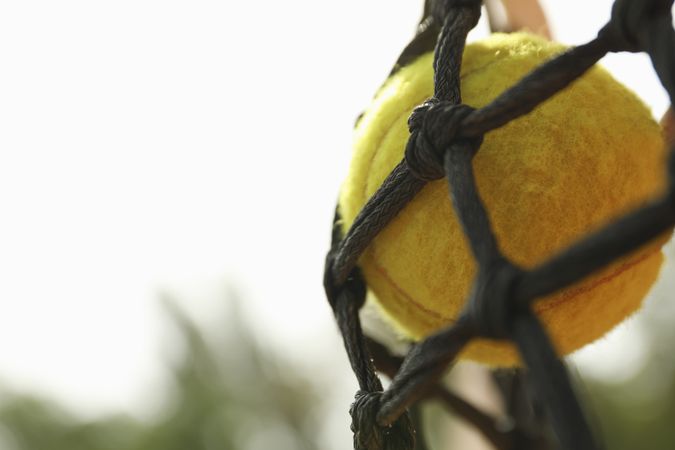 Tennis ball in net, close up and space for text
