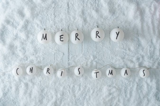 Wooden table background with snow and lights ball decoration reading “Merry Christmas”