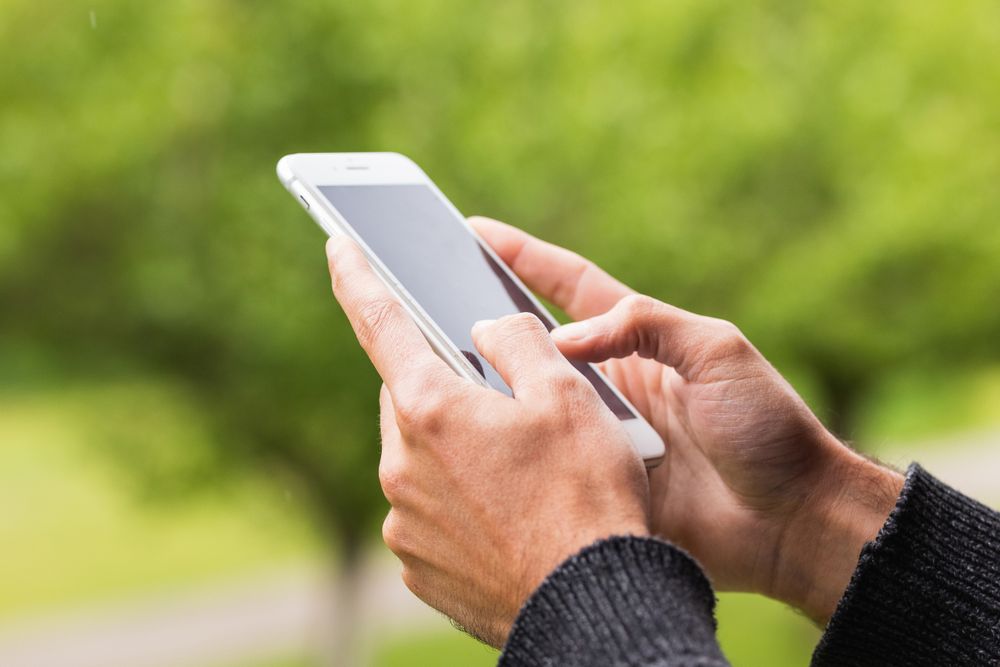 Anonymous man browsing on mobile phone on terrace