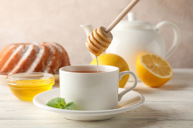 Cup of tea, lemon, mint, honey, dipper and pie on wooden background, close up
