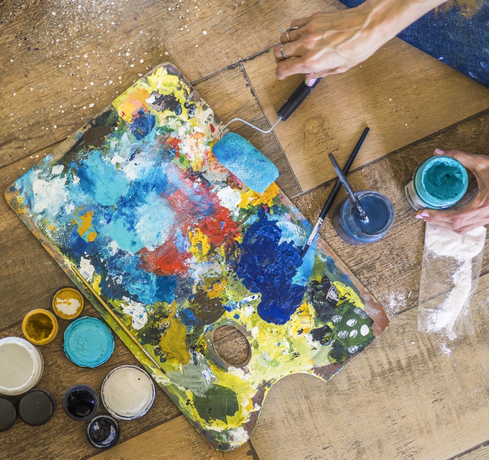 High angle view of brushes, pallete, oils, acrylics and other elements of a painter artist. Art workshop. Background.