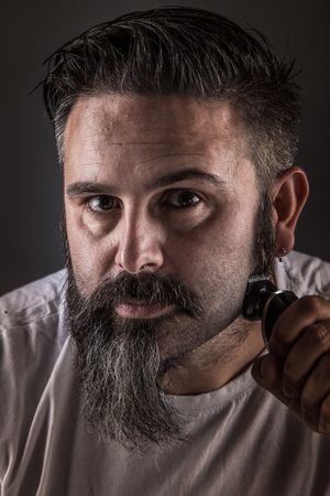 Barber shaving beard and looking at camera