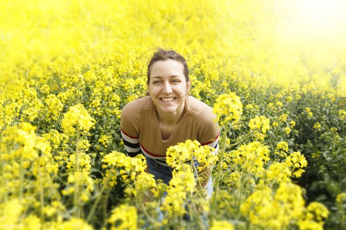 Woman crouched in yellow field smiling