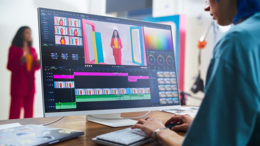 In A Vibrant Film Studio, A Young White Female Editor Fine-tunes A Colorful Video Project On Her Monitor, Showcasing A Woman In A Red Suit, Enhancing Storytelling In Modern Videography.