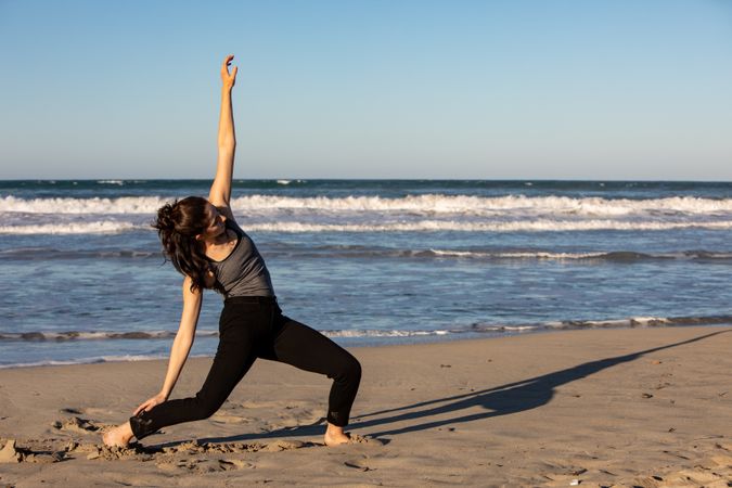 Young woman dancing and posing near water on shore