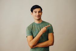 Happy Hispanic male pointing right in neutral room, copy space