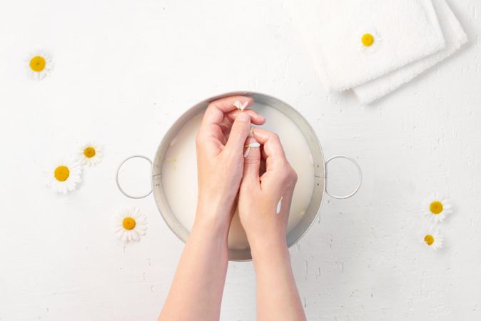 Home spa treatment with woman’s hands above bowl of spa water