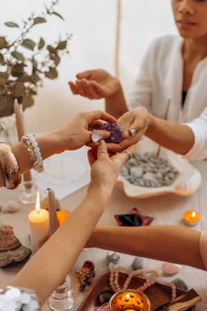 Cropped image of women sitting at table with gemstones and candles