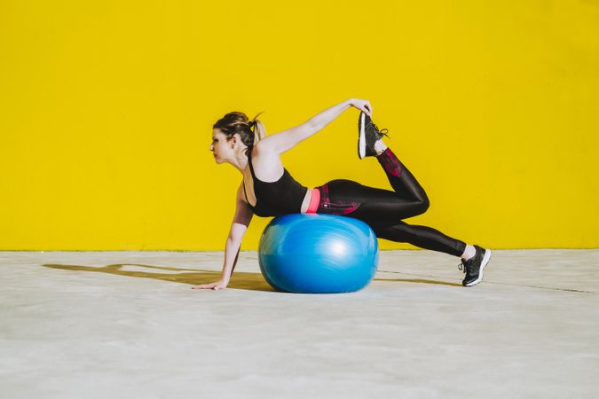 Woman stretching while leaning on ball