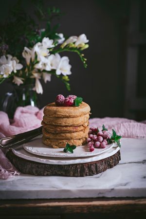 Pile of raspberry pancakes with honey on plate
