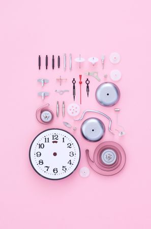 Neatly disassembled clock on pink background
