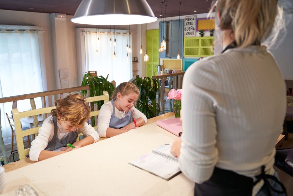 Happy children taking notes before cooking with anonymous mom
