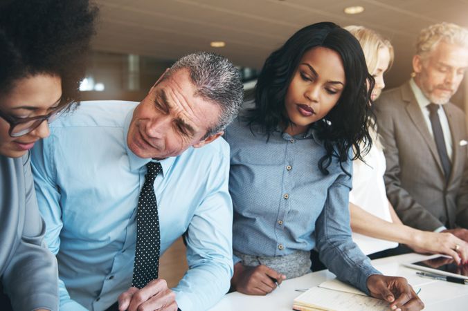 Multi-ethnic group of colleagues standing discussing plans at work