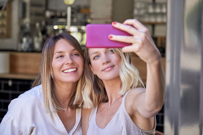 Young female friends taking selfie in cafe