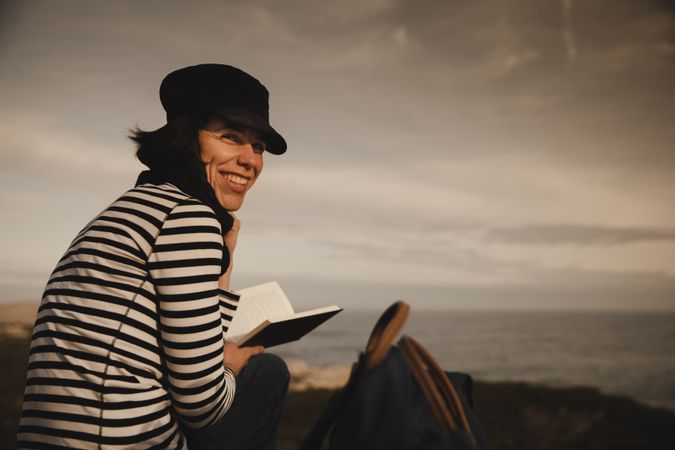 Woman with book on grass near lighthouse