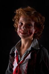 Vertical photo of a child disguised as a zombie with blood and glitter