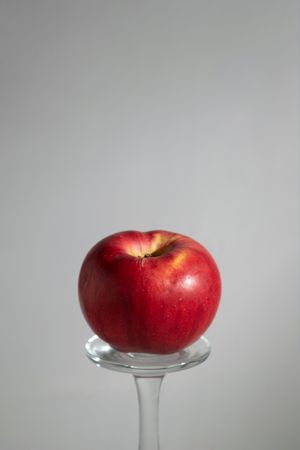 Red apple balancing on glass