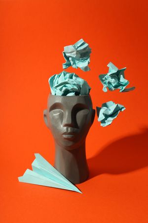 Grey bust of head on red background with crumpled paper, vertical