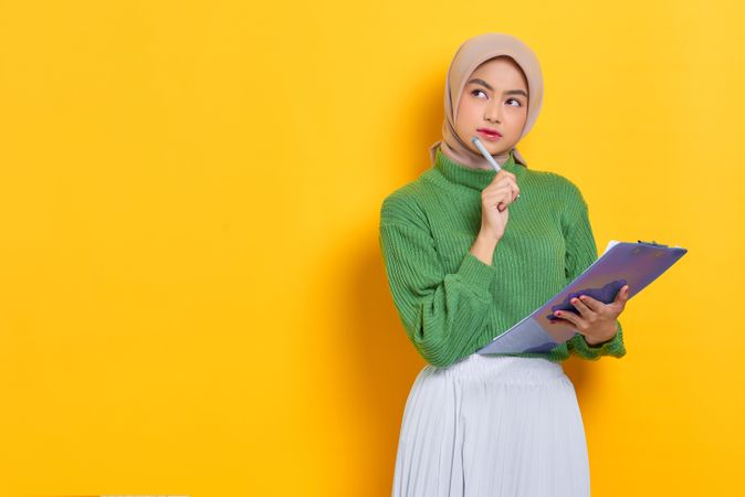 Woman in headscarf with clipboard and pen in studio shoot