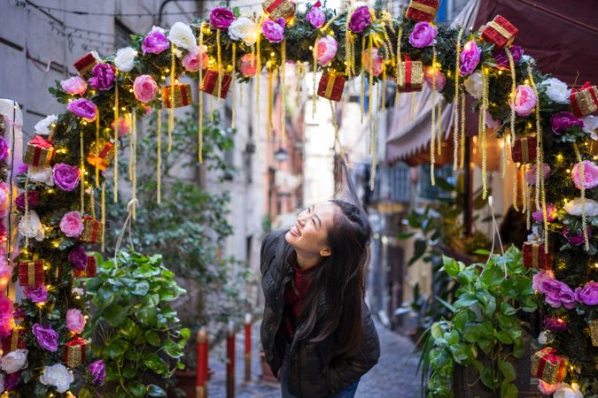 Satisfied Asian female traveler in casual wear walking on festive beautiful street