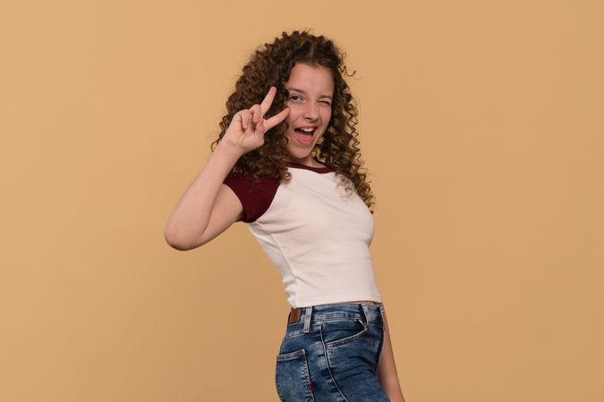 Playful young girl making peace sign and winking