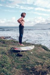 Fit man putting on wetsuit at seaside