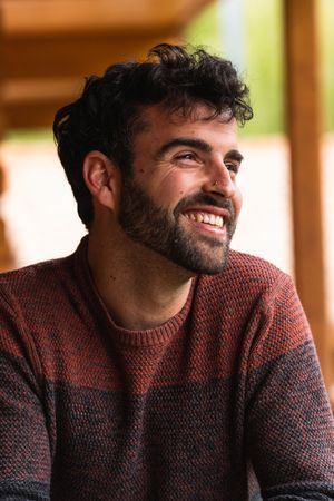 Cheerful man chilling on terrace and looking away