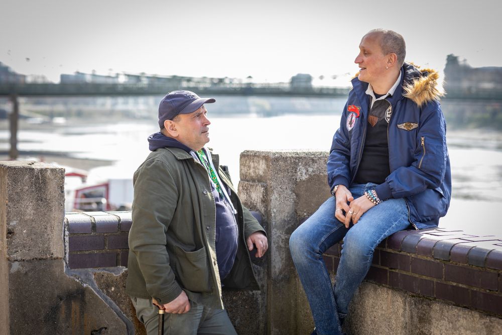 Two male friends sitting by the river and talking