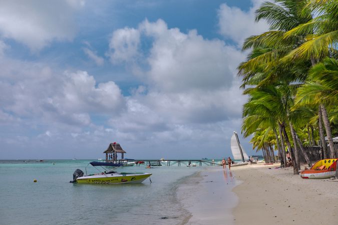 Boat in water on busy Mauritius beach on cloudy day