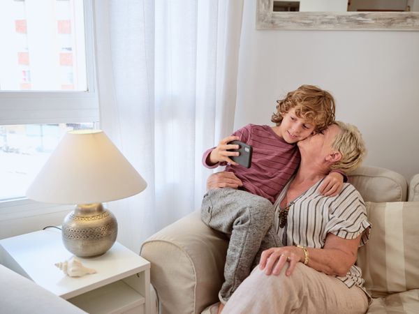 Grandson hugging and taking selfie with grandmother