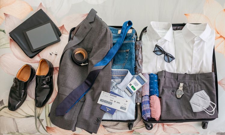 Businessman suitcase prepared for business trip with covid passport on mobile