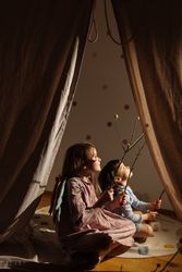 Kids sitting and playing on mat behind tent indoors