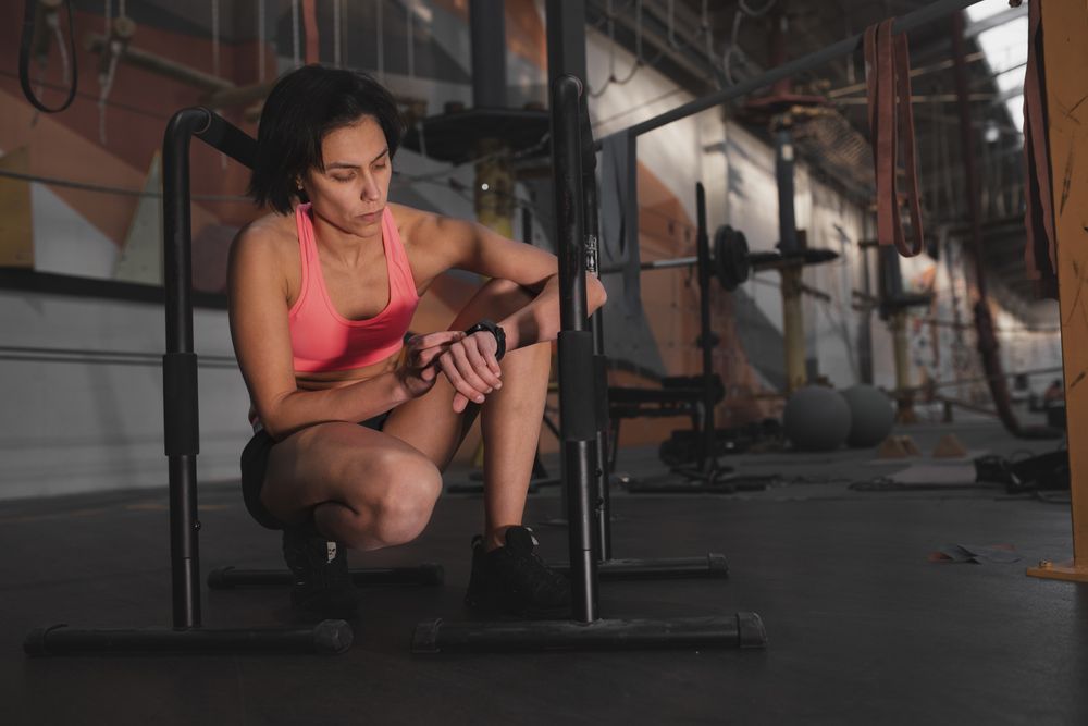 Athletic woman looking at watch between parallel bars in gym