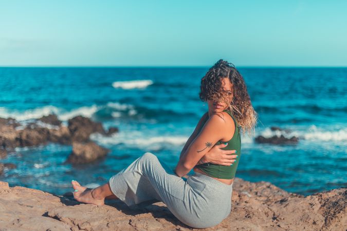 Stylish woman sitting near sea