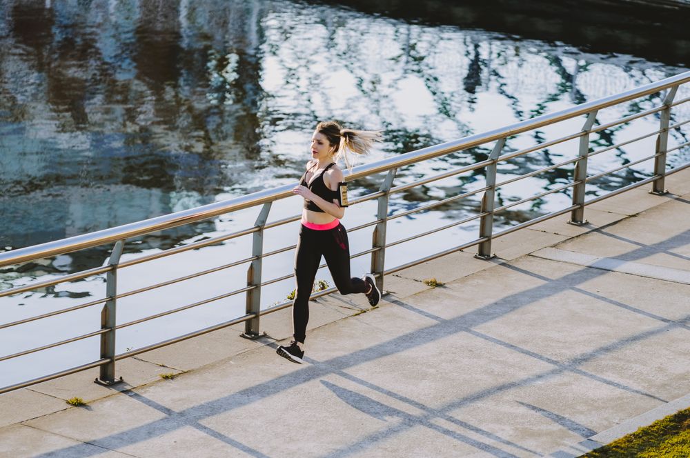 Woman running on embankment near water